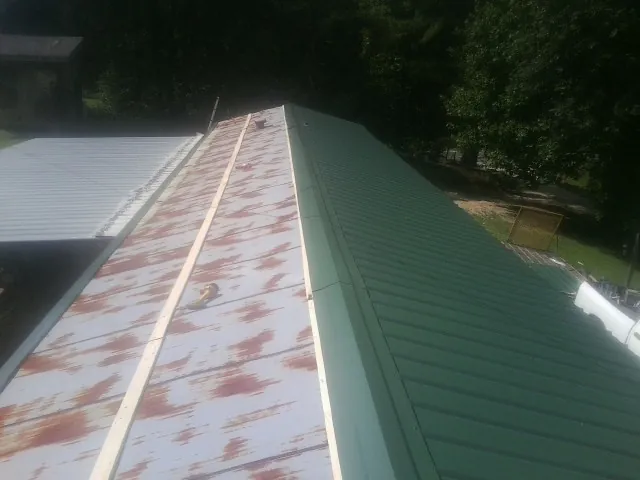 Old rusted panels beside newly installed green metal roofing — Wind Damage Roof Repair by Roofing Brothers in Rockport