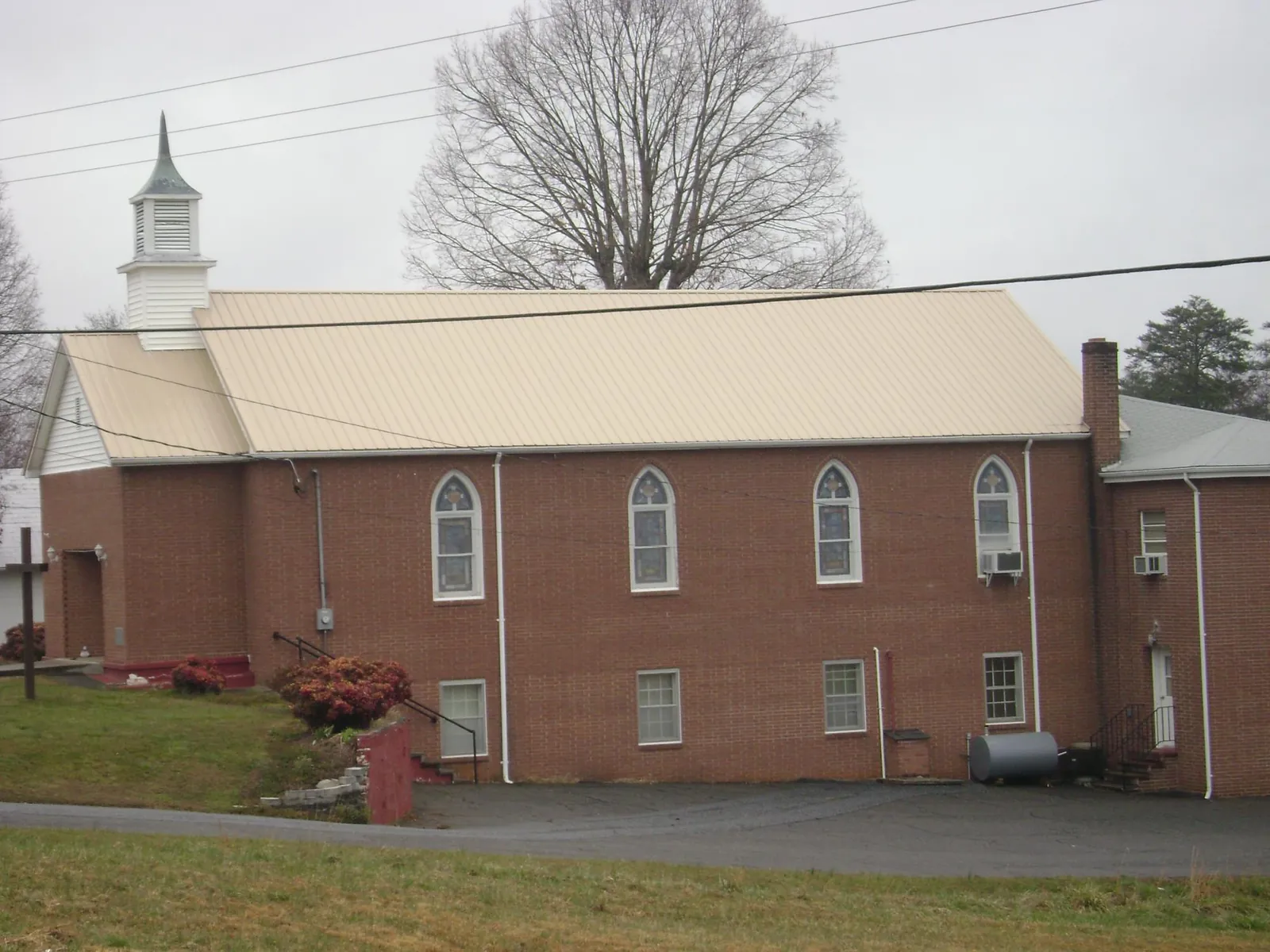 New tan metal roof on a brick church with a white steeple in Rockport